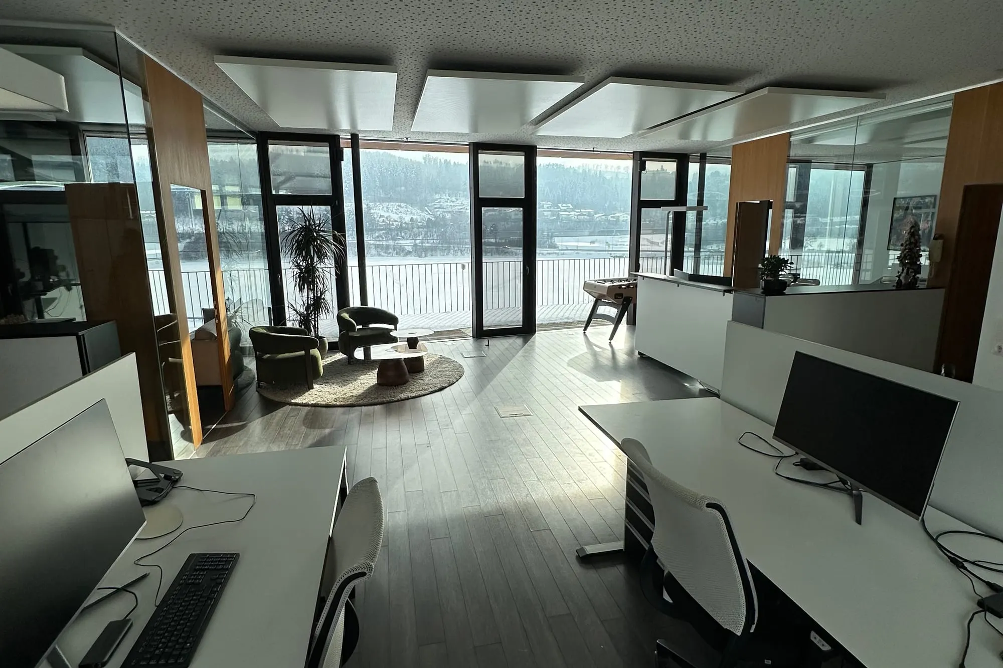 Vue à travers le bureau de Kaino sur les postes de travail et les écrans, devant la façade vitrée