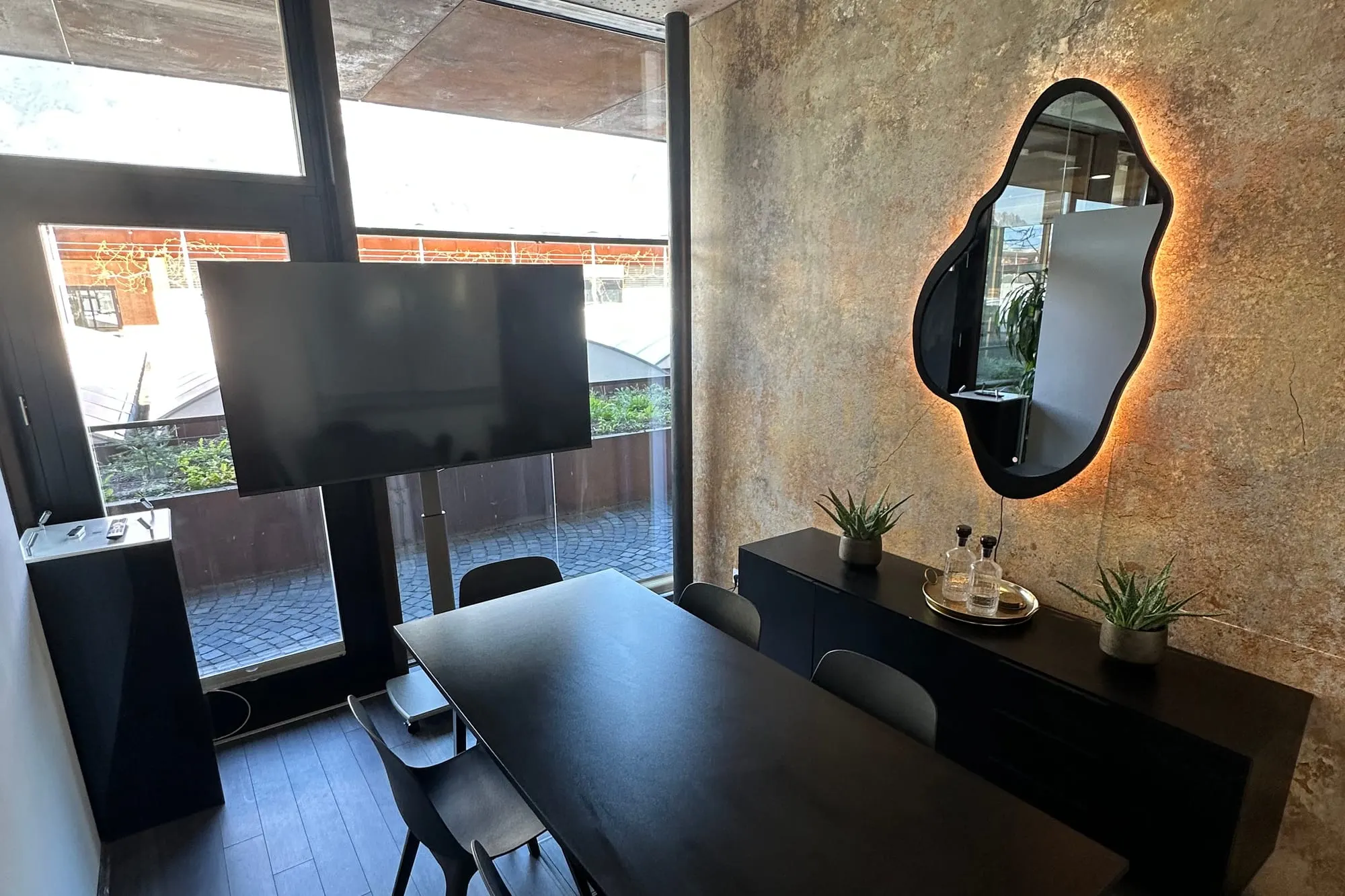 La salle de réunion avec sa longue table, son écran et son miroir mural rétroéclairé