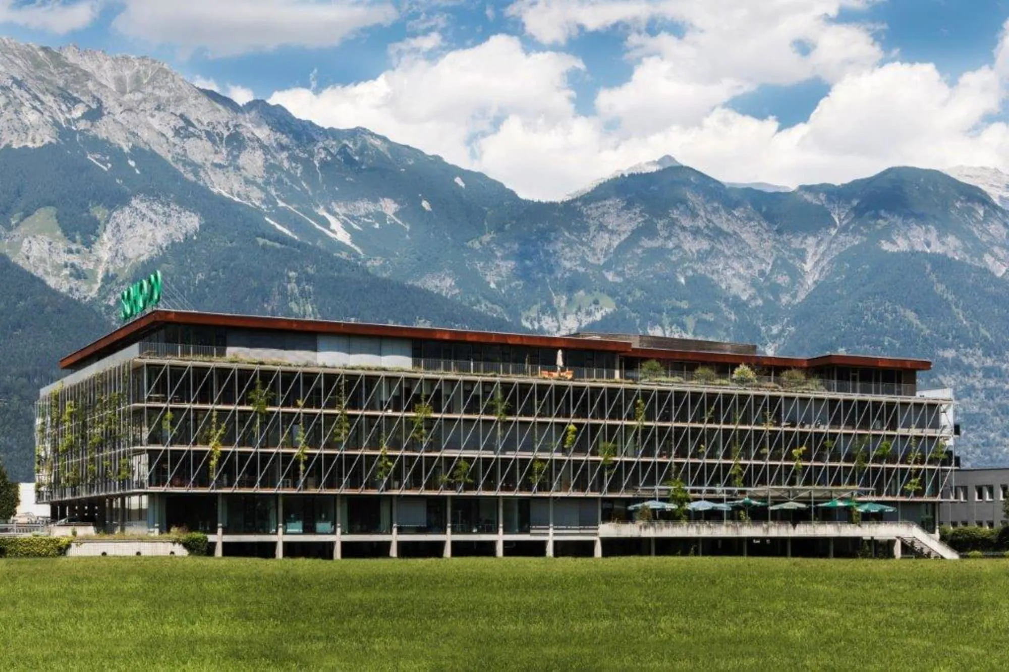 The SOHO 2.0 office building in Innsbruck with its planted façade, the Nordkette mountains behind